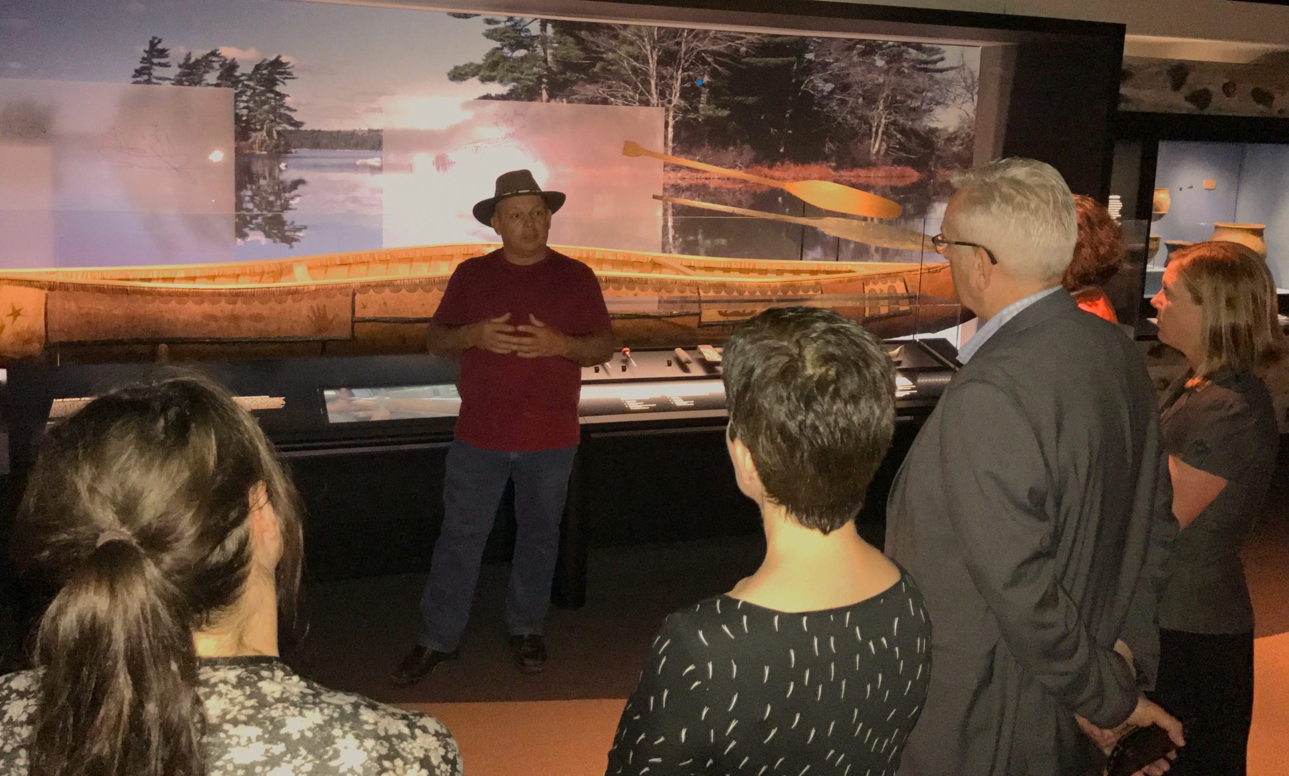 Man speaking to group of visitors in front of exhibit